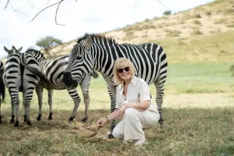 Woman crouching to feed a zebra