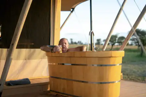 Man relaxing in outdoor wooden bathtub