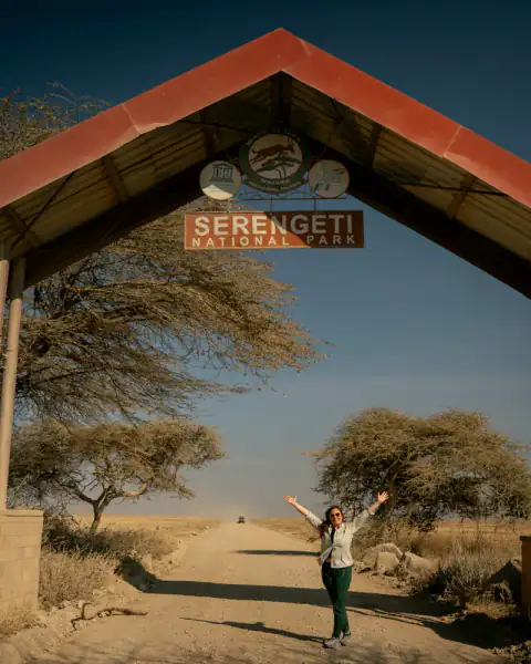 Arms raised under the Serengeti National Park arch