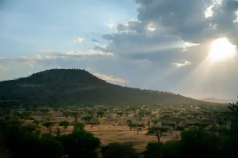 Sunbeams breaking over a Serengeti hill
