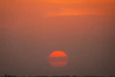 Deep red sun dropping to the horizon