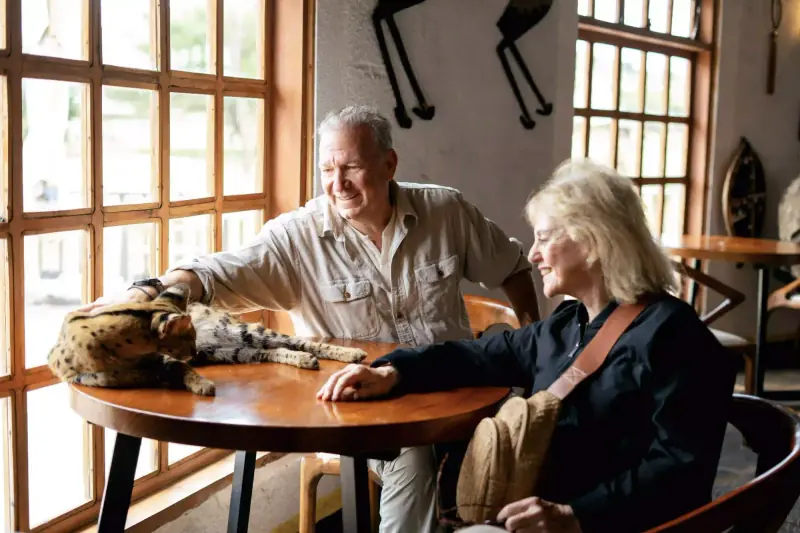 Couple petting a serval cat at lodge table