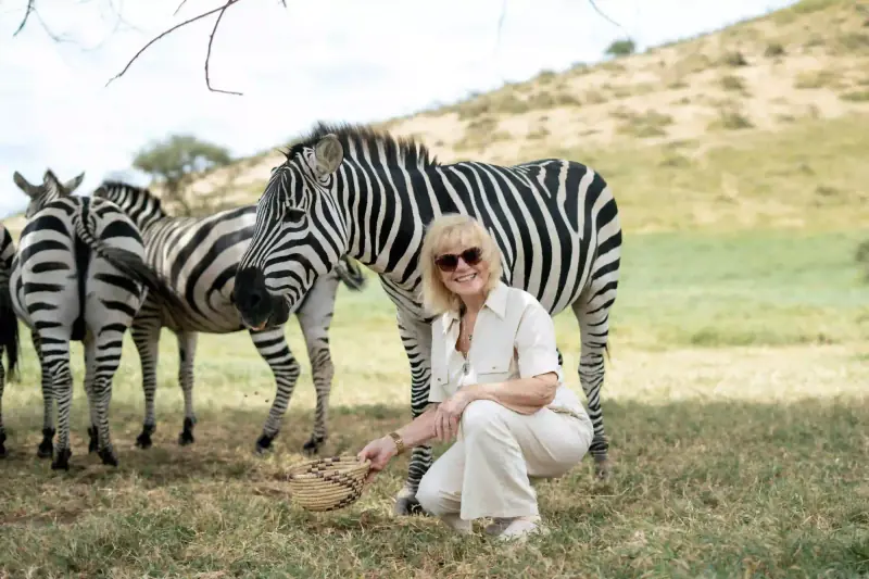 Woman crouching to feed a zebra