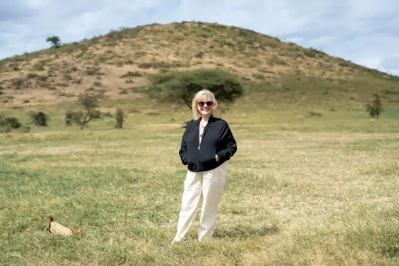 Woman standing alone before savanna hillside