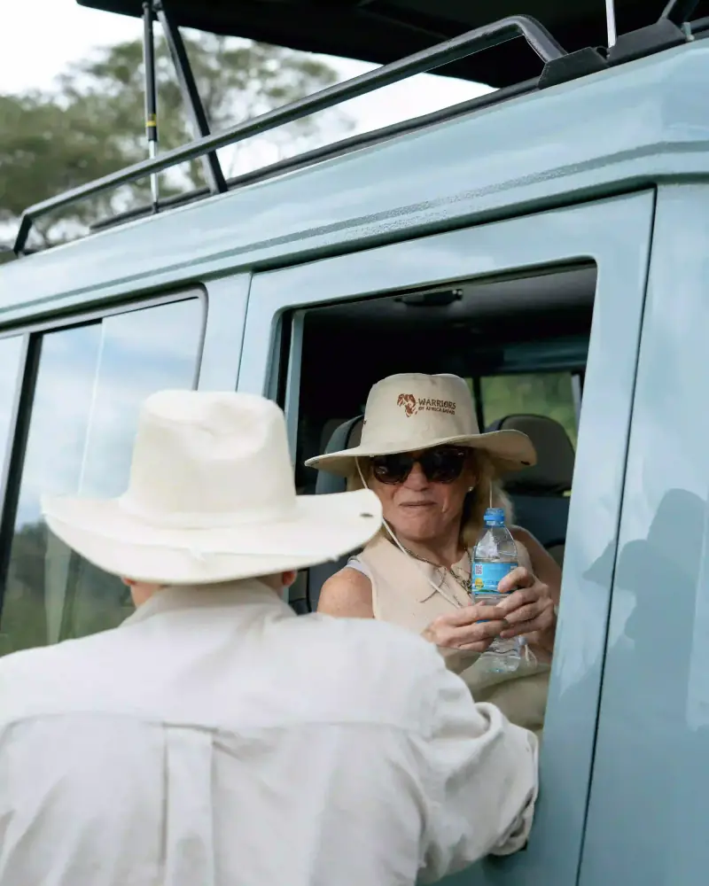 Woman passing water bottle through vehicle window