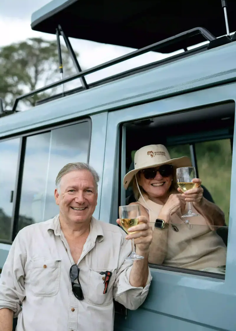 Couple toasting wine through safari vehicle window