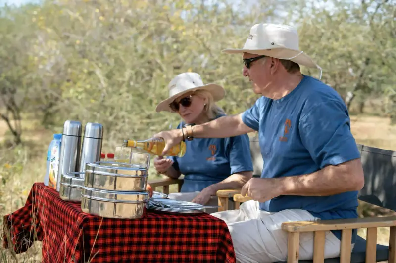 Couple pouring wine at bush lunch table