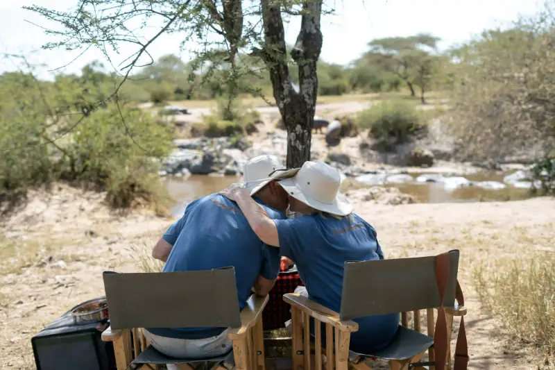 Couple embracing with river and hippos behind