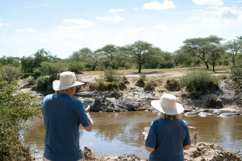 Guests photographing hippos from riverbank