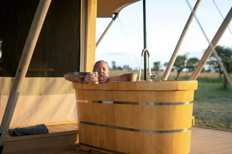 Man relaxing in outdoor wooden bathtub