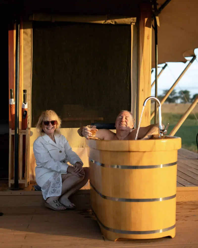 Couple toasting beside outdoor wooden bathtub