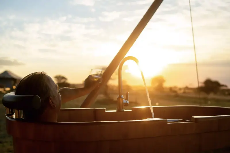 Man in bathtub toasting at sunset
