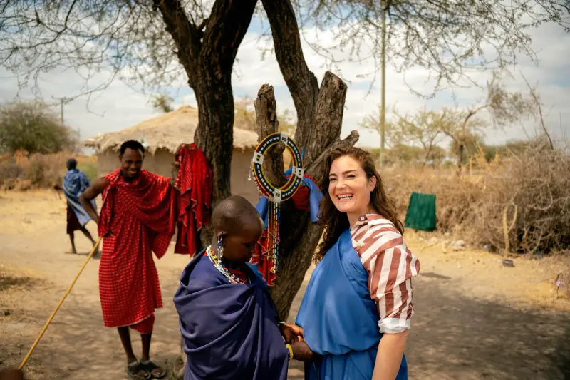 Guest wrapped in a Maasai shuka meeting warriors under an acacia