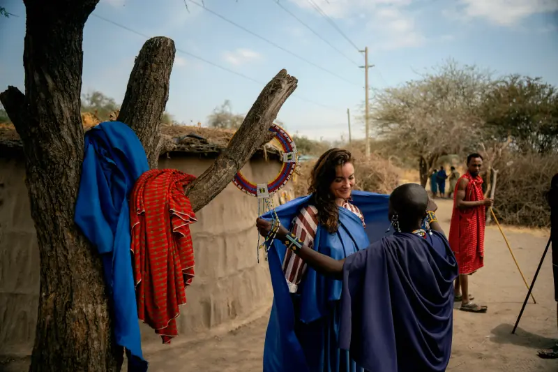 Maasai woman fitting a beaded collar on a visiting guest