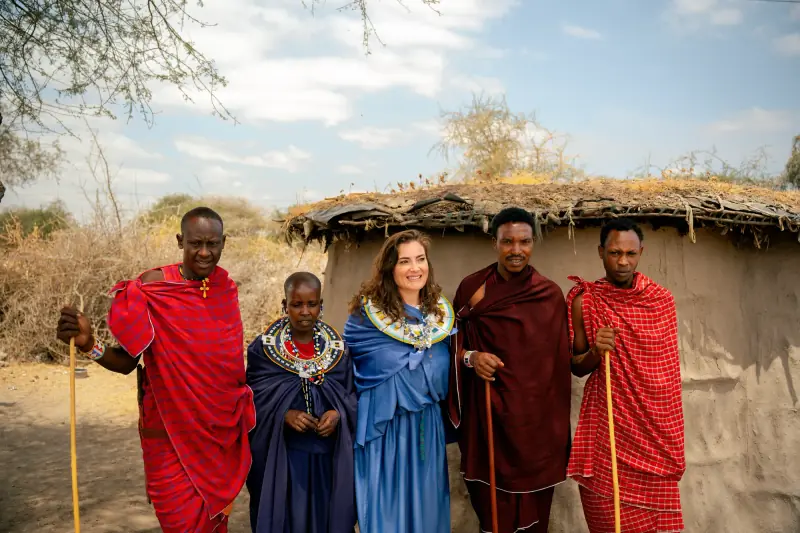 Guest standing with Maasai men and women outside a boma