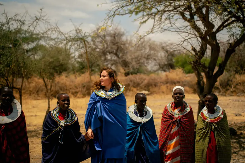 Guest in a blue shuka walking with Maasai women