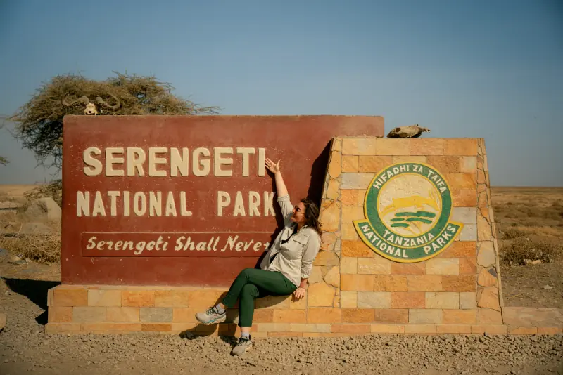 Guest sitting on the Serengeti National Park sign
