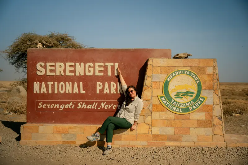 Guest sitting on the Serengeti National Park sign