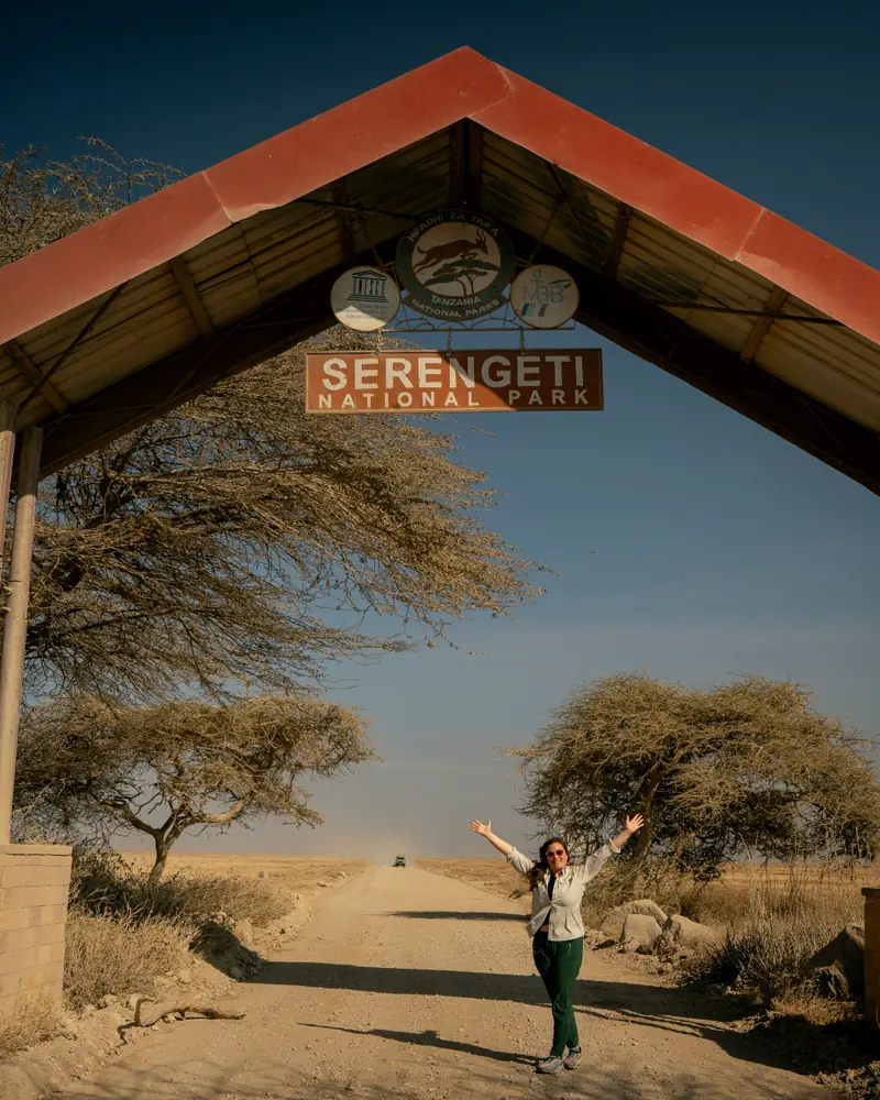 Arms raised under the Serengeti National Park arch