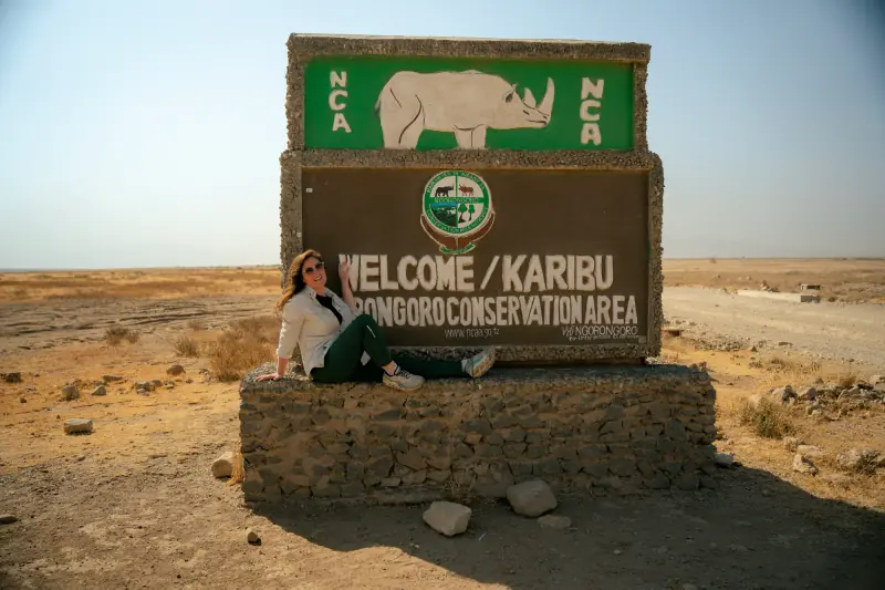 Guest at the Ngorongoro Conservation Area welcome sign
