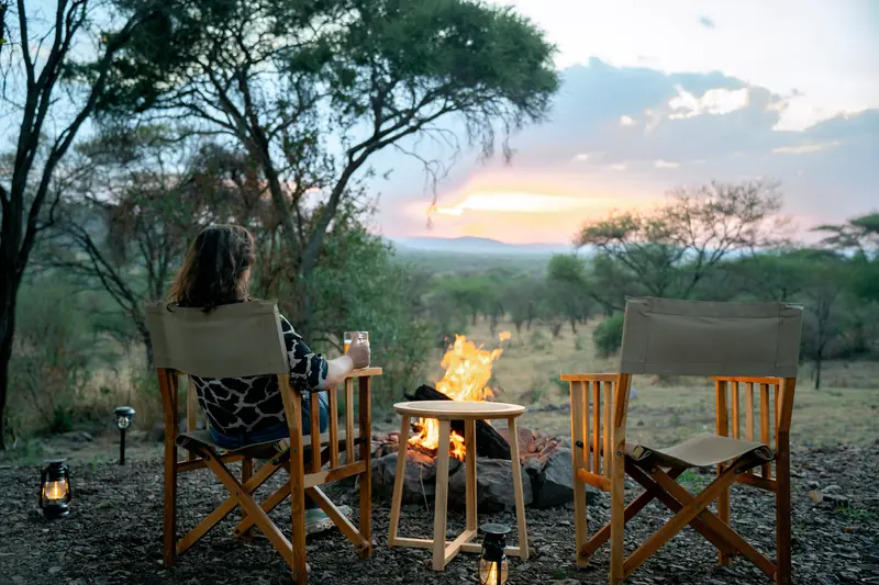 Fire lit beside the camp chairs at dusk