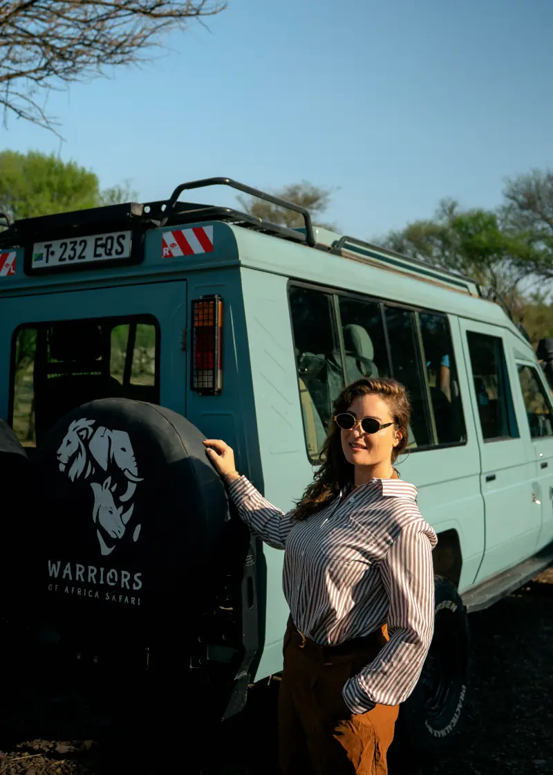 Guest beside the safari vehicle in the morning sun