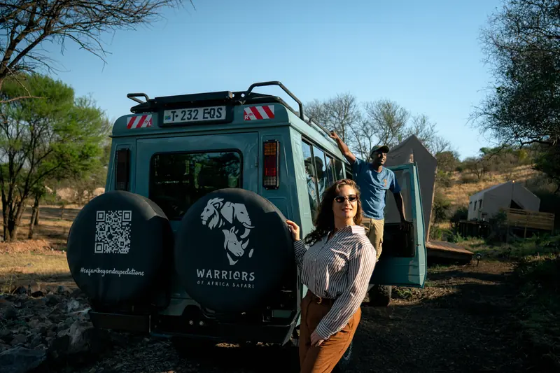 Guest and crew by the vehicle at the tented camp