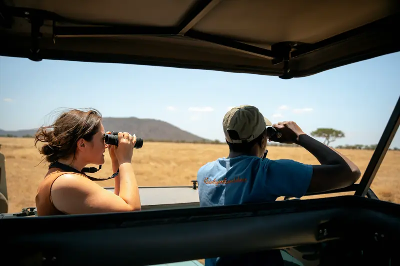 Guest and guide glassing the plains with binoculars