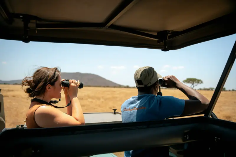 Guest and guide scanning the plains with binoculars
