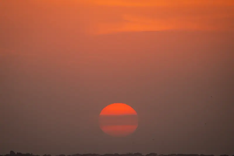 Deep red sun dropping to the horizon