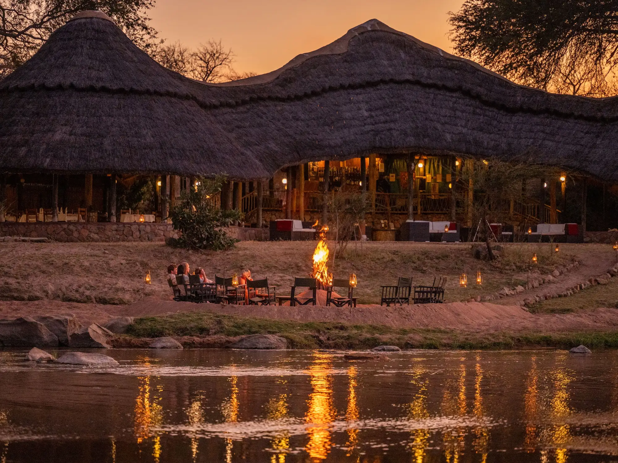 The lodge and fire pit on the river at dusk